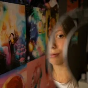 Person beside colorful wall art.